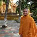 Cambodian Monk smiling in front of a pagoda