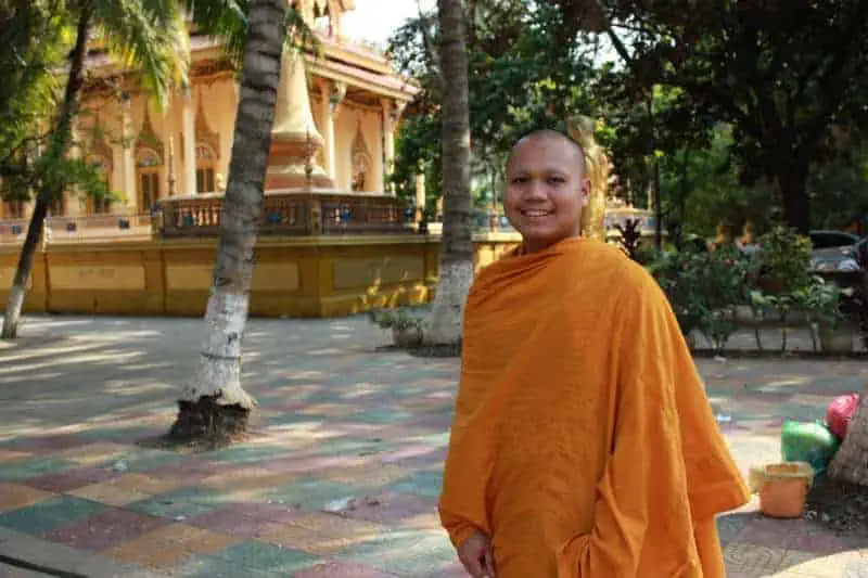 Cambodian Monk smiling in front of a pagoda