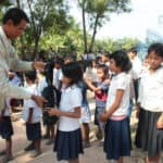 Education in Cambodia - teacher handing out backpacks to students