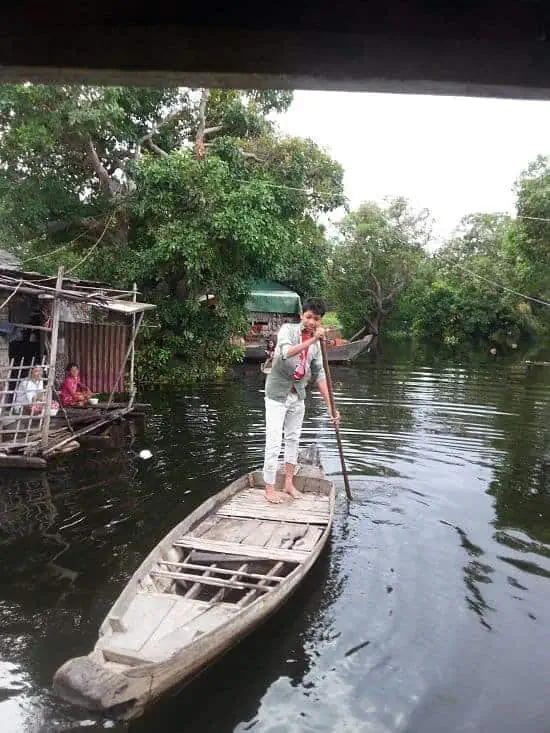 Phare Circus staff Kimhak Hun navigates boat through flooded forest