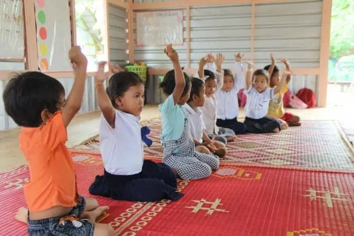 Students raise arms in classroom at Phare Ponleu Selpak school