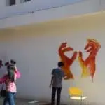 Phare Ponleu Selpak students making street art on a building wall