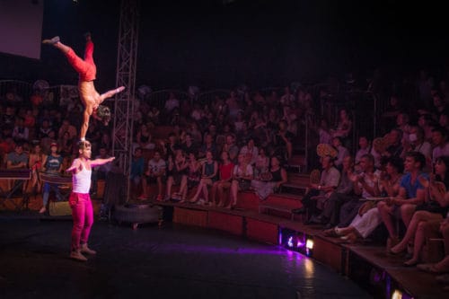 Phare Circus performer does one-hand handstand on the head of another on the big top stage