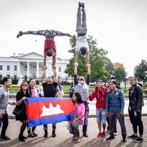 Phare Circus performers take group photo with Cambodian flag in front of The White House