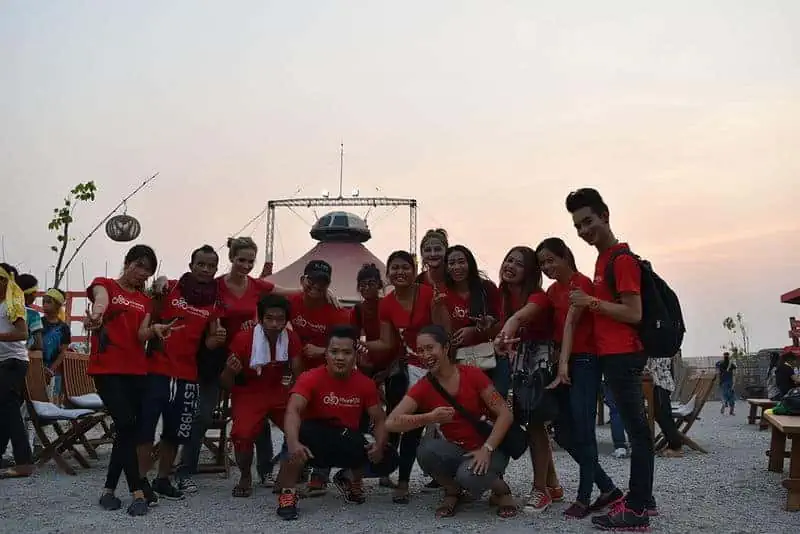 Phare Circus staff and artists in red t-shirts pose for group photo in front of the big top