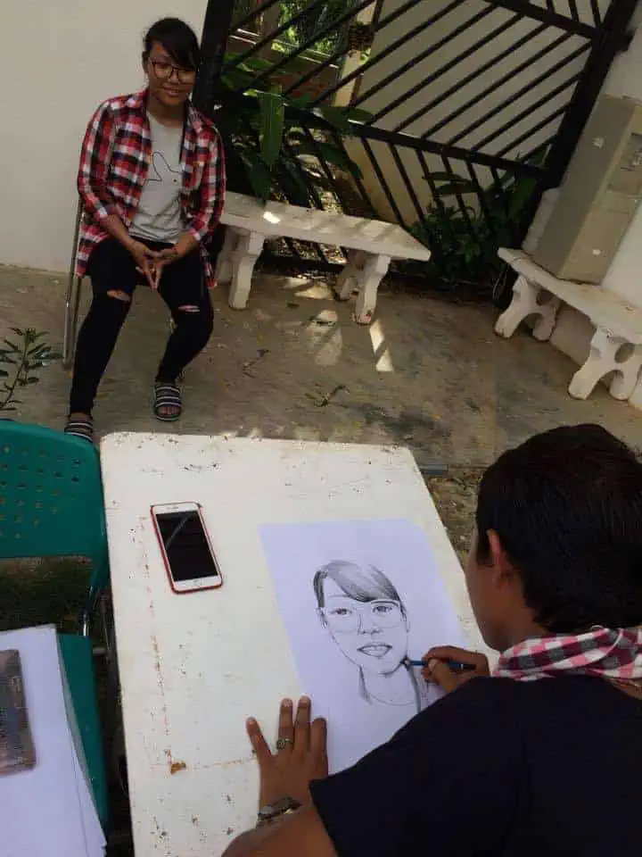 Young woman has portrait sketched by Phare Ponleu Selpak visual artist