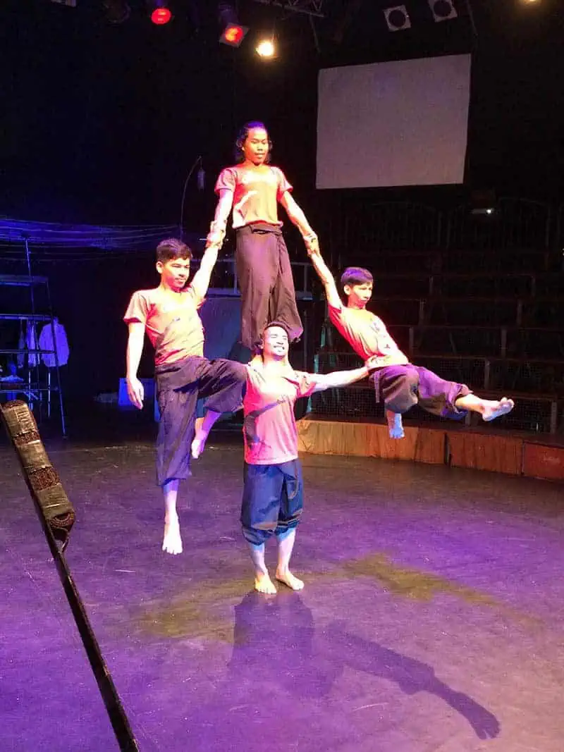 Phare Circus performers and staff demonstrate human pyramid - 4 men in red t-shirt and farmer pants