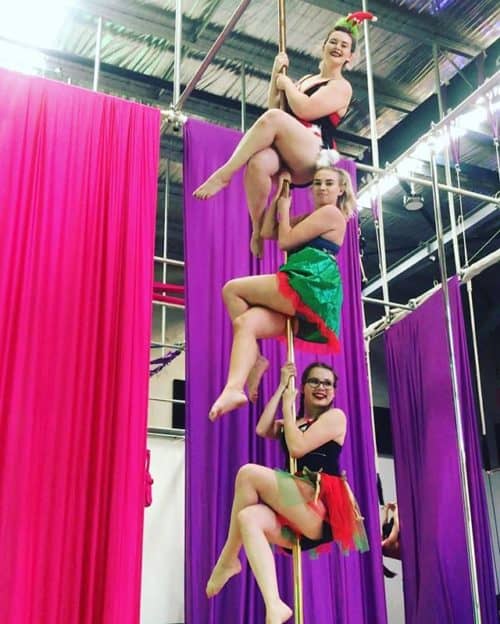 Two young female aerial acrobats practicing the splits on silk