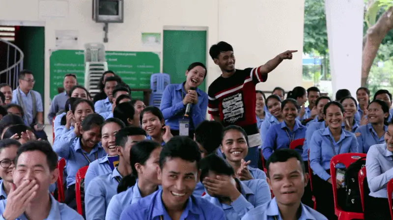 "See You Yesterday" performer smiling and laughing with a group of Cambodian students