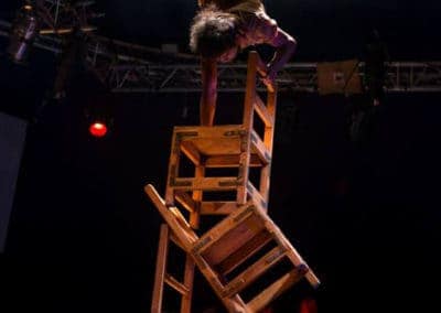 Phare Circus show "Chills": male performer does handstand atop several balancing wooden chairs