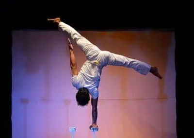 Phare Circus performance "Eclipse": male performer doing one-hand handstand on balancing stick