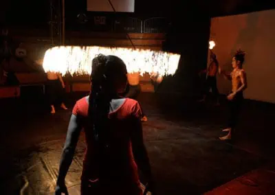 Phare Circus performance "Eclipse": female performer watching others do fire jump rope on circus stage