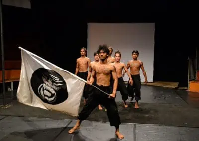 Phare Circus performance "Eclipse": male performers standing behind performer holding white flag with black design