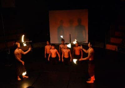 Phare Circus performance "Eclipse": male performers juglging fire batons in front of others kneeling on stage
