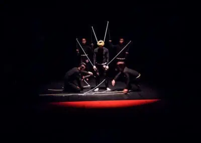 Phare Circus performance "Influence" - survival of the fittest: performers in black costumes attach strings to a "puppet"