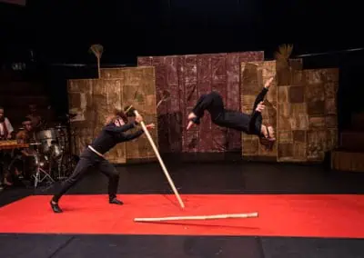 Phare Circus performance "Influence" - survival of the fittest: male perfomers in black battle with bamboo sticks
