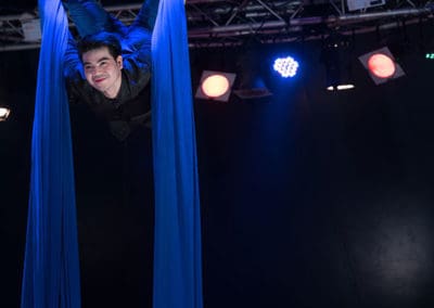 Phare Circus performance "Khmer Metal": smiling aerial silk artist inverted above bar stage