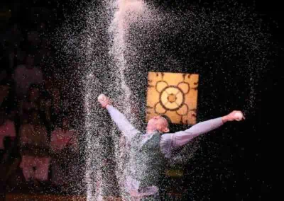Phare Circus performance "White Gold"- male artist juggling under shower of rice in Cambodia